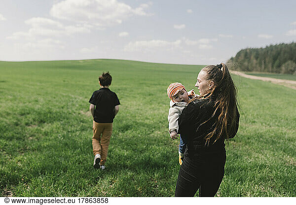 a woman walks with her children on a green meadow