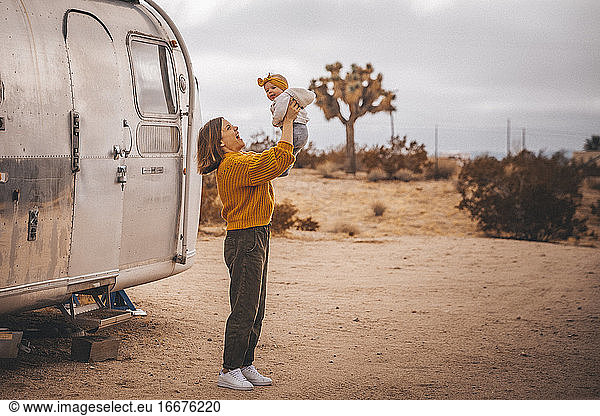 A woman with a baby is near an RV trailer  Joshua Tree  California
