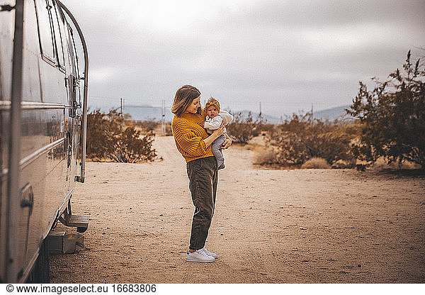 A woman with a baby is near an RV trailer  Joshua Tree  California