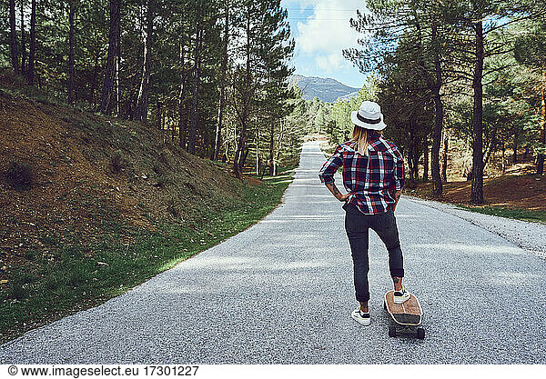 A woman with a skateboard on a mountain road
