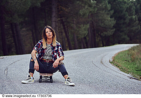 A woman with a skateboard on a mountain road