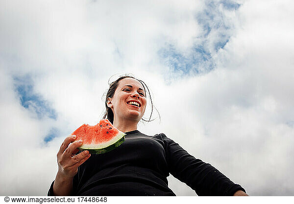a woman with a watermelon on the background of clouds