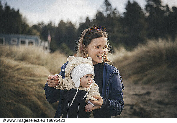 A woman with an infant is standing on the Californian beach