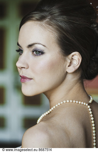 A woman with brown hair  wearing a pearl necklace.