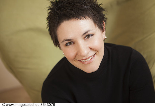 A woman with short spiky brown hair  wearing a black turtleneck sweater. Smiling and looking up.