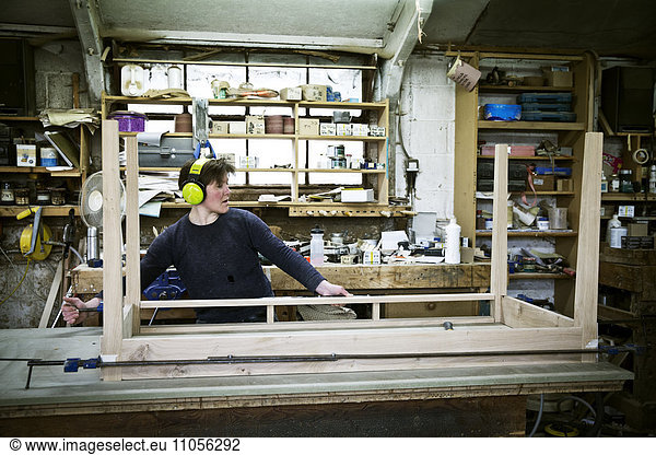 A woman working in a furniture maker's workshop  assembling a table.