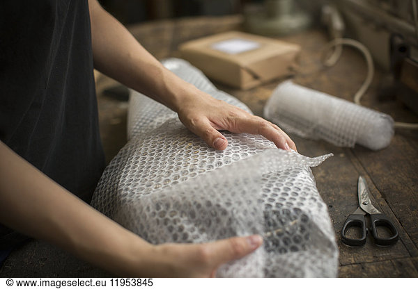 A woman wrapping an item in bubble wrap  a parcel being prepared for despatch.