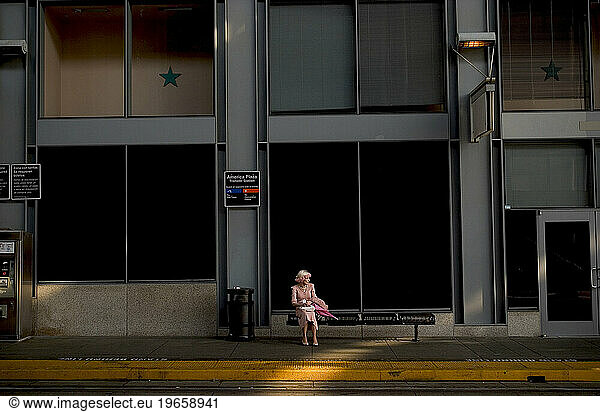 A women in a pink dress waits for the train.
