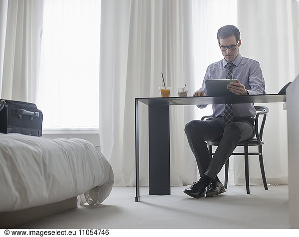 A working day. A man seated at a laptop computer  working in a hotel bedroom.