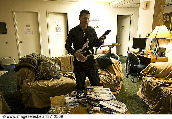 A youg man relaxes in the living room of the Mt. Washington Observatory by playing a rock music video game.