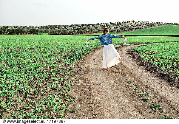 a young and beautiful woman walks barefoot through the countryside