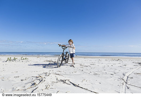 A young boy biking on a sandy beach