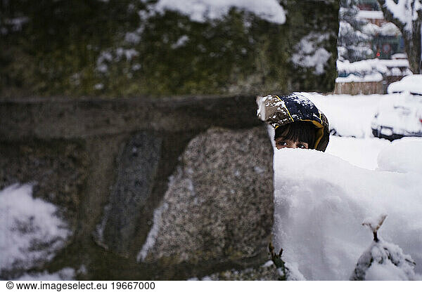 A young boy hides behind a stone wall during a snowball fight during a rare blizzard in Vancouver.