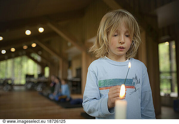 A young boy lights incense at an alter during a Buddhist family retreat on Vashon Island  Washington.