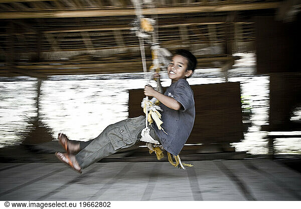 A young boy smiling on a swing.