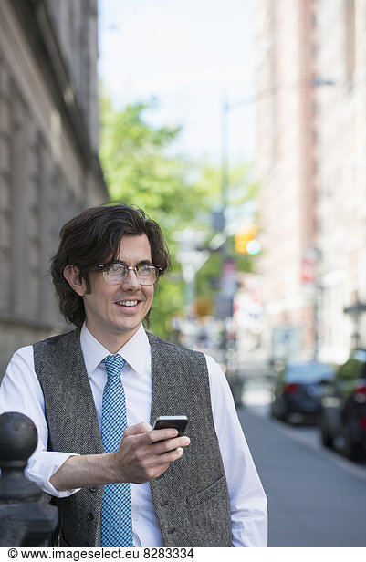 A Young Business Man On The Street Checking His Smart Phone.