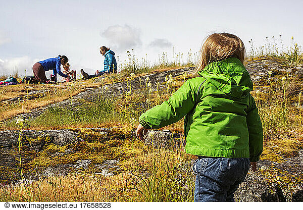 A young child walks toward parents on a mossy rock