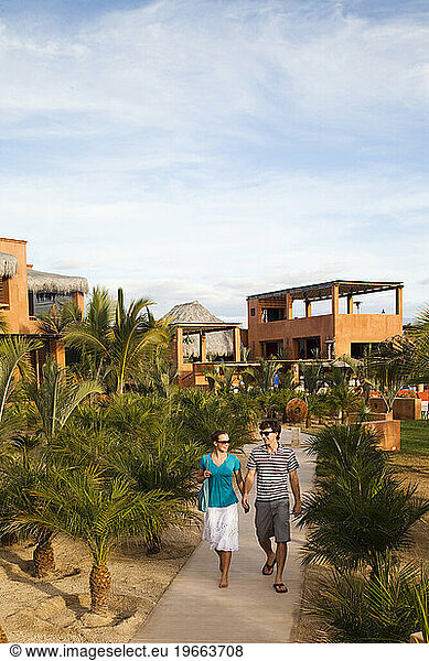 A young couple walk down the path from a boutique hotel on the beach in Pescadero  Baja California Sur  Mexico.