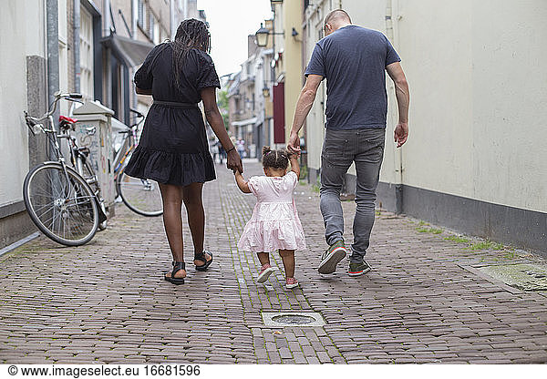 A young couple walking with their daughter
