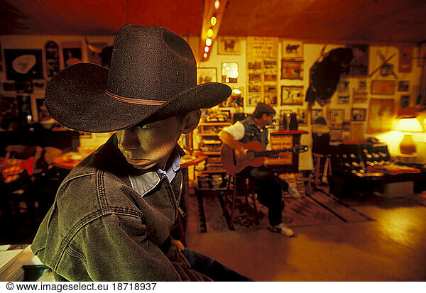 A young cowboy listens to Spanish guitar music at night after a bullfight.