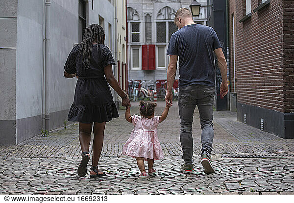 A young family walking through the streets of a European city