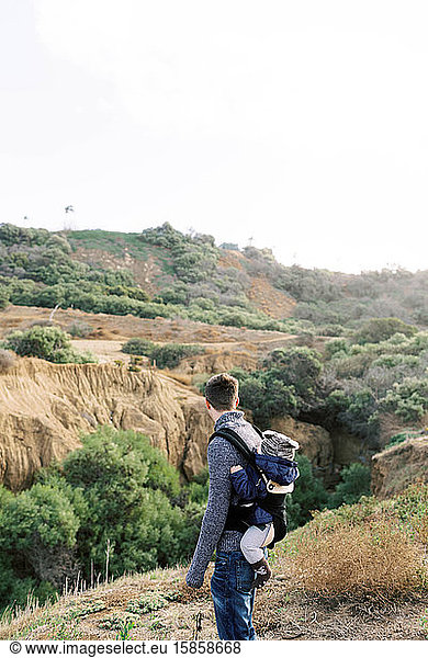 A young father babywearing his son during a hike in Southern Cali.