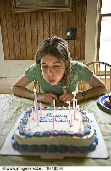 A young girl blows out the birthday candles on a decorative cake at her home in Maine.