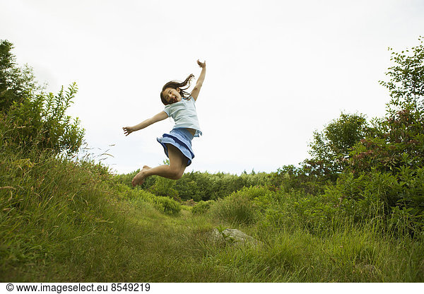 A young girl  leaping for joy  kicking up her heels in the air.