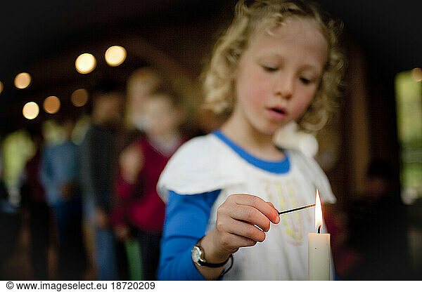 A young girl lights incense at an alter during a Buddhist family retreat on Vashon Island  Washington.