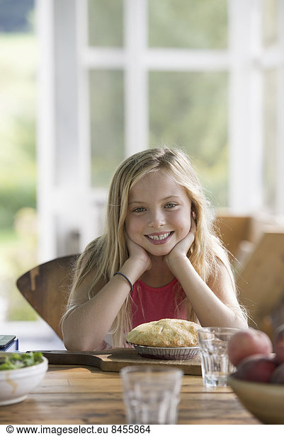 A young girl looking at a pastry pie  smiling.
