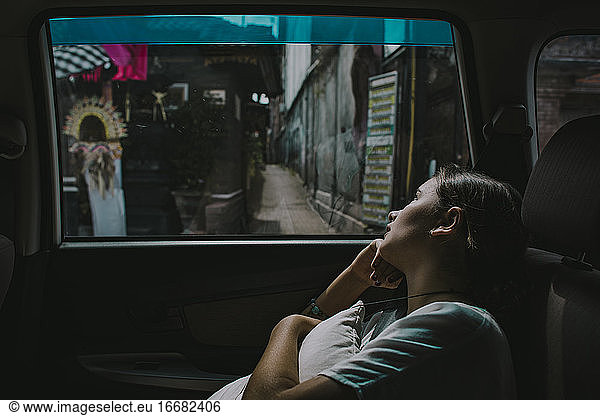 A young girl looks out of the window of a car in Seminyak Bali
