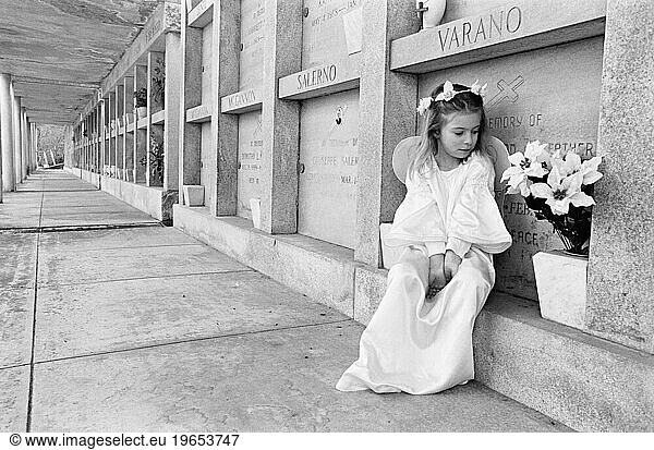 A young girl sitting in front of a mausoleum.