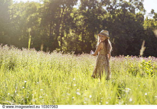 A young girl walking in a field in the sunshine