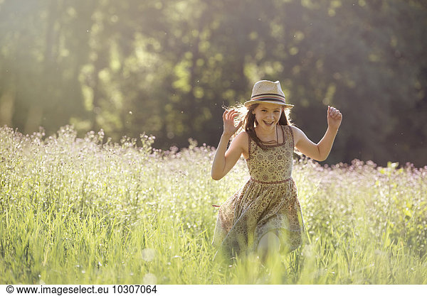 A young girl walking in a field in the sunshine