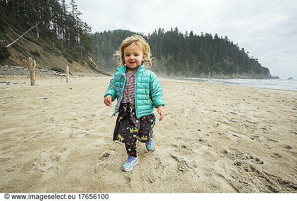 A young girl walks on a foggy beach
