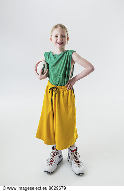 A young girl wearing oversized basketball jersey shorts and shoes holding a basketball Anchorage alaska united states of america
