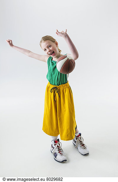 A young girl wearing oversized basketball jersey shorts and shoes throwing a basketball Anchorage alaska united states of america