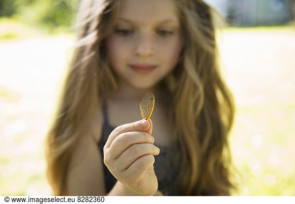 A Young Girl With Long Blonde  Holding A Delicate Lacey Patterned Discarded Butterfly Wing.