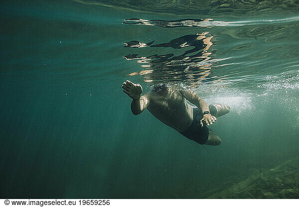 A young hispanic male swims through cold  blue water.