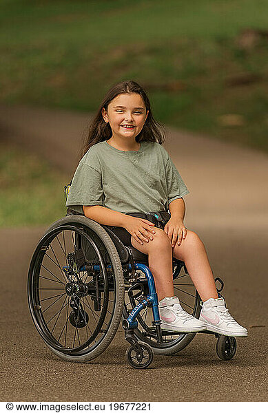 A young lady smiling in a wheelchair at a park