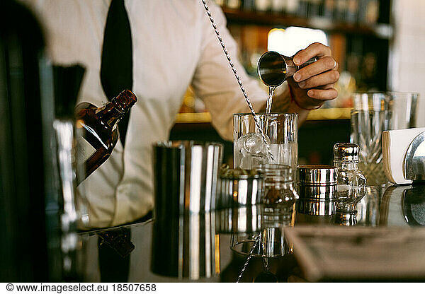 A young man bartender works in a bar made a cocktail.