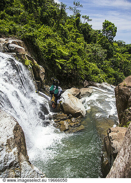 A young man does a back flip into a swimming hole during a river adventure in Puerto Rico.