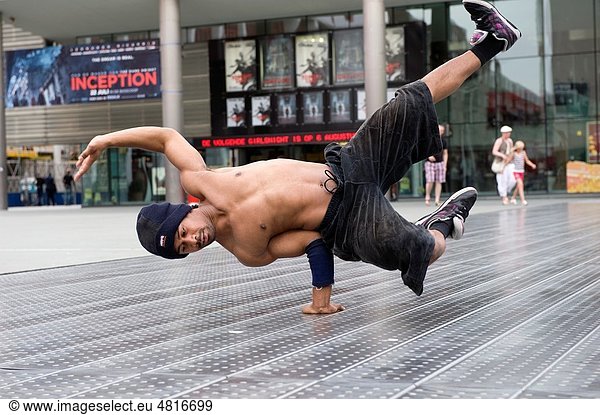 A young man is training for streetdance or breakdance on a square downtown Rotterdam It is a warm  summer night