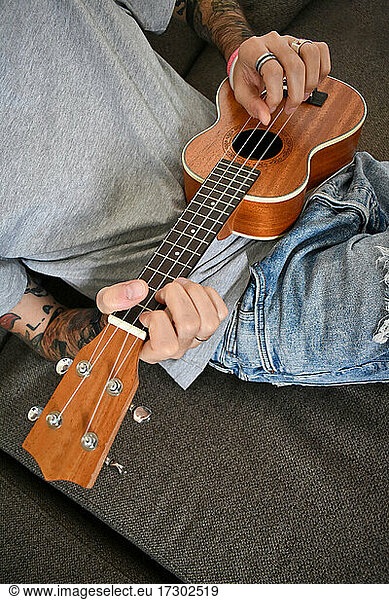 A young man plays a wooden ukulele