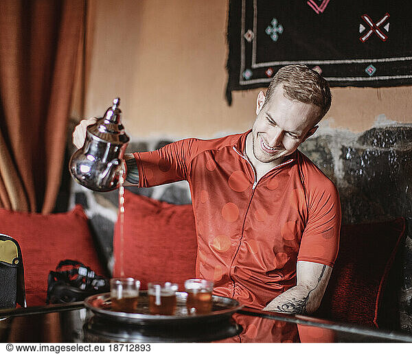 A young man pours a traditional cup of Moroccan Tea from a kettle