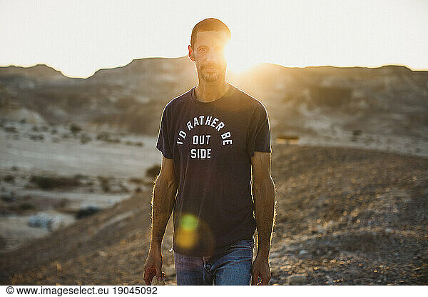 A young man standing in the desert looking forward in sunset