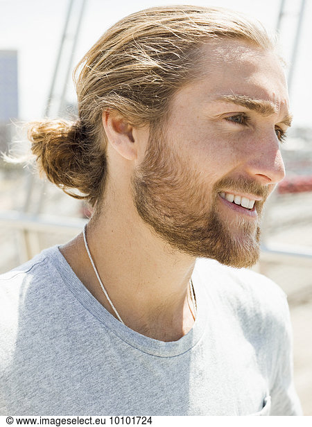 A young man with beard  red hair and ponytail.