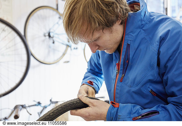 A young man working in a cycle shop  repairing a bicycle.
