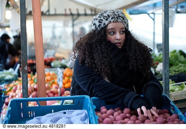 A young North-African woman sels groveries at the Rotterdam saturdaymarket.