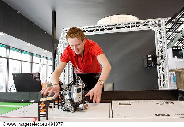 A young student of a technical univesity demonstrates his robots on a large table during a tradefair.
